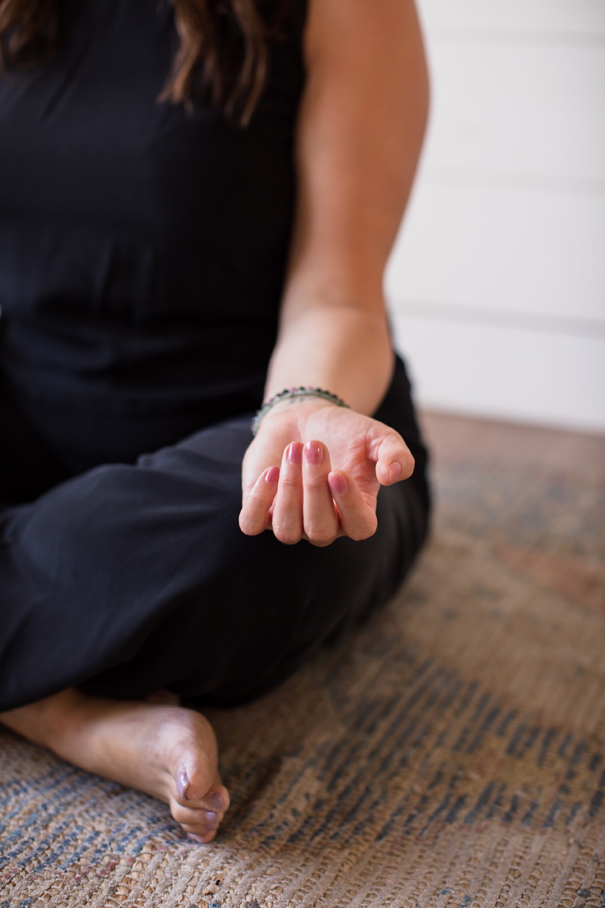 Close-up of Heather Flynn seated cross-legged in meditation, one hand resting open on her knee
